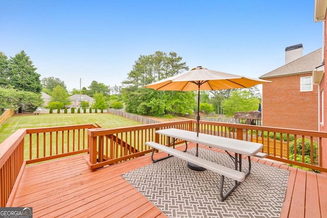 wooden deck with a lawn, outdoor dining area, and a fenced backyard