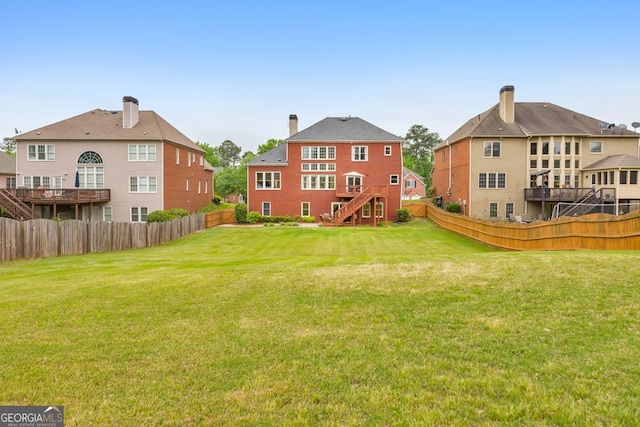 rear view of house featuring a fenced backyard, stairs, and a lawn