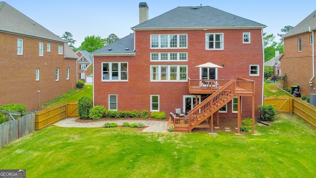 back of house with a deck, stairway, a fenced backyard, a chimney, and a lawn