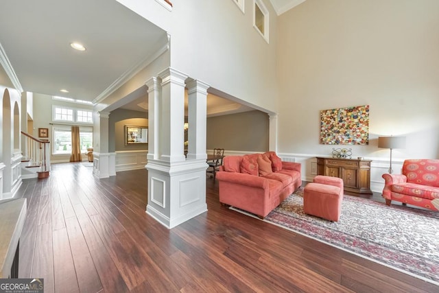 living area with crown molding, wainscoting, dark wood-style floors, and stairway