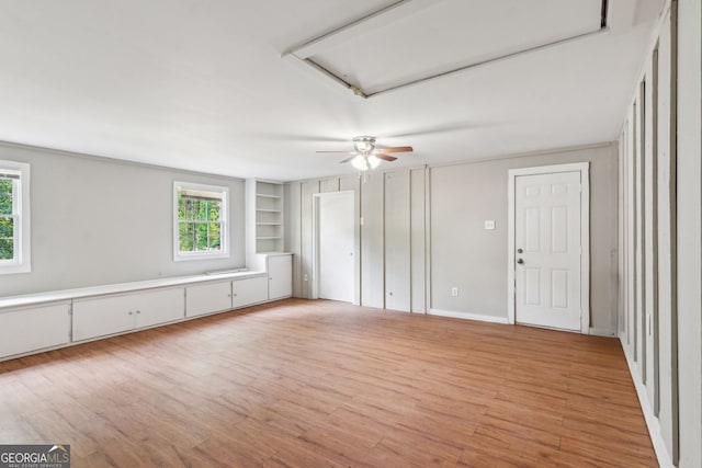 unfurnished bedroom with ceiling fan, attic access, and light wood-style floors