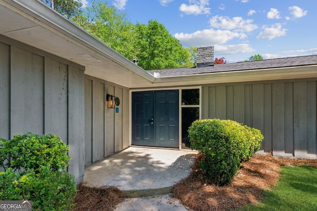 view of exterior entry featuring board and batten siding and a chimney