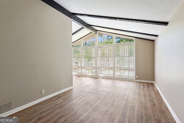 unfurnished living room featuring baseboards, vaulted ceiling with beams, wood finished floors, and visible vents