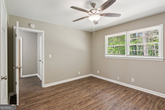 spare room featuring a ceiling fan, baseboards, and dark wood-style floors