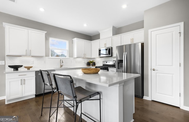 2108 Amaryllis Dr, Grayson, GA 30017 - kitchen with dark wood finished floors, white cabinetry, a kitchen island, appliances with stainless steel finishes, and a sink