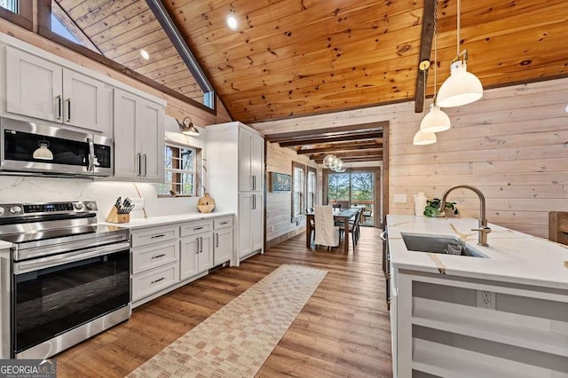 kitchen featuring a sink, light countertops, wood ceiling, wooden walls, and stainless steel appliances