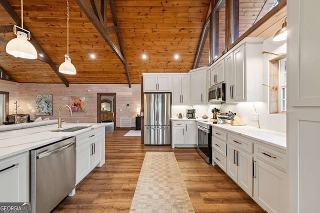 kitchen featuring a sink, open floor plan, vaulted ceiling with beams, and stainless steel appliances