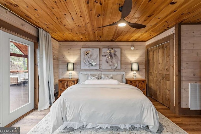bedroom featuring wooden walls, visible vents, light wood-type flooring, and wooden ceiling