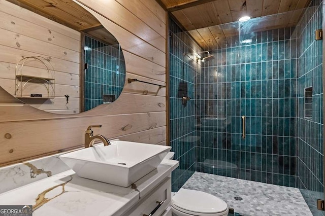 bathroom featuring toilet, wooden walls, vanity, and a stall shower