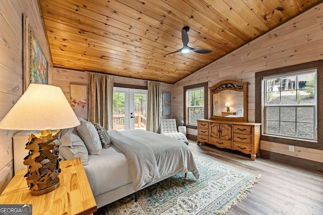 bedroom with access to exterior, french doors, wooden walls, and vaulted ceiling