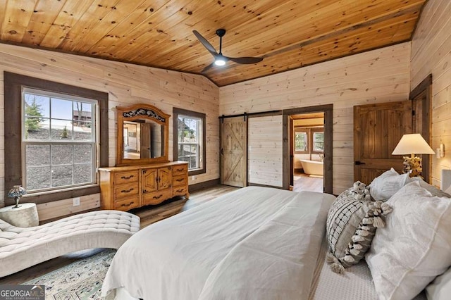 bedroom with a barn door, wooden walls, multiple windows, and wood ceiling