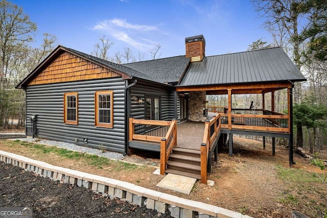 exterior space featuring a chimney, a deck, and log veneer siding