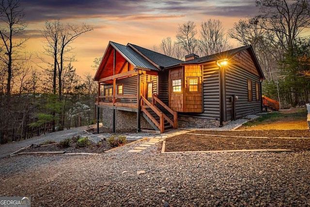 rustic home with stairway, a chimney, and log veneer siding