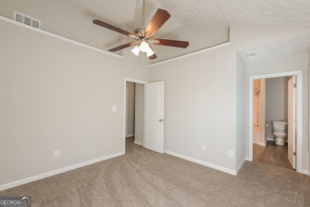 unfurnished bedroom with visible vents, baseboards, carpet, ensuite bath, and lofted ceiling