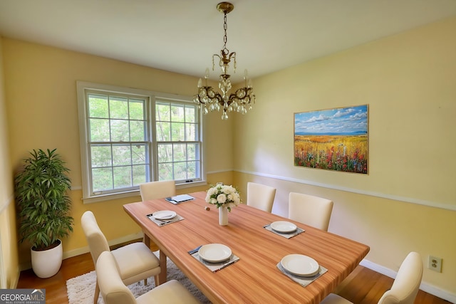 dining space featuring baseboards, wood finished floors, and an inviting chandelier