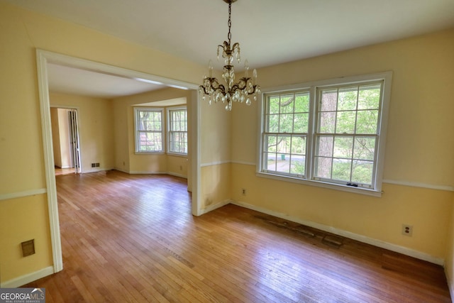 unfurnished dining area featuring baseboards, an inviting chandelier, and light wood-type flooring