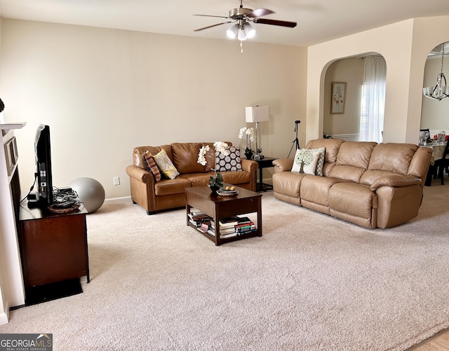 living area with arched walkways, carpet, and a ceiling fan