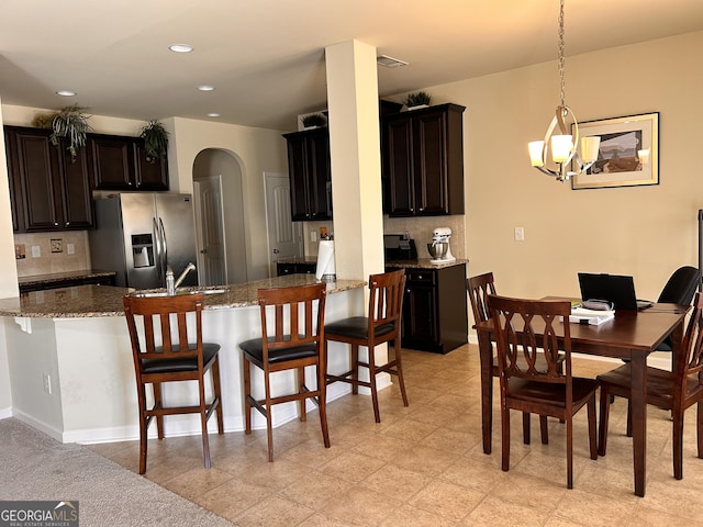 dining area with a chandelier, arched walkways, baseboards, and recessed lighting