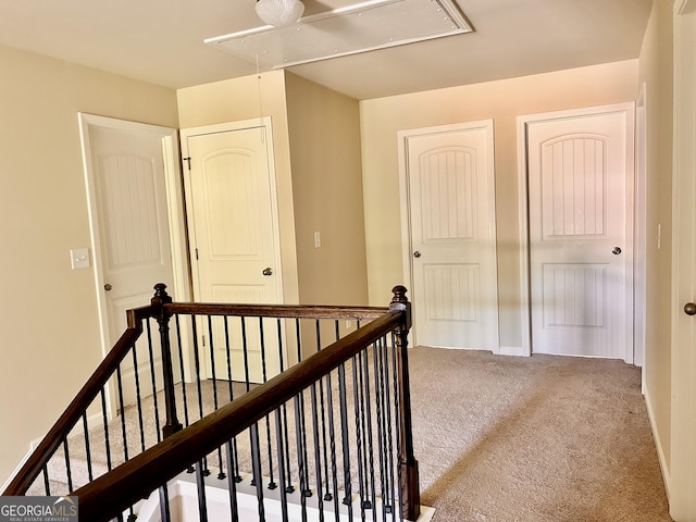 corridor featuring carpet floors, an upstairs landing, and attic access