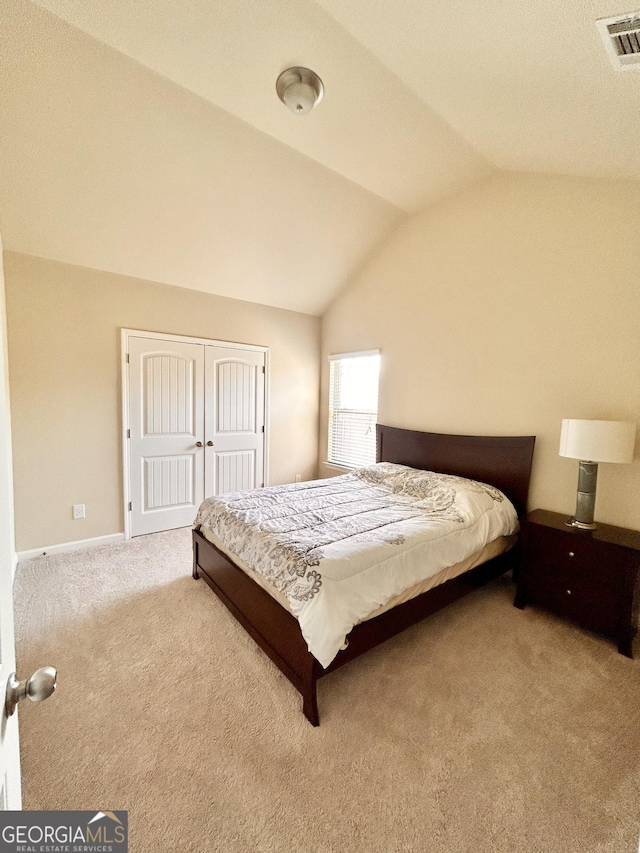 bedroom with a closet, visible vents, carpet floors, lofted ceiling, and baseboards