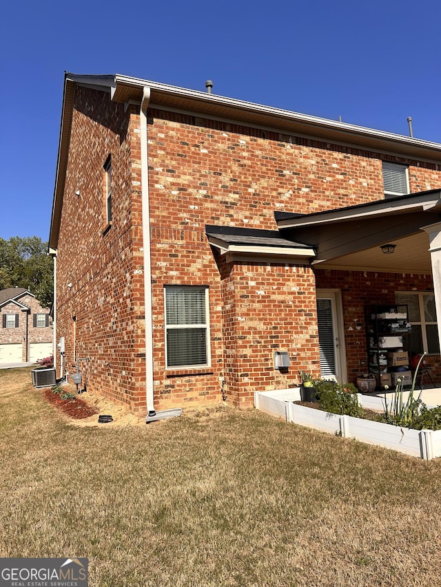 rear view of property with brick siding, central AC, and a lawn