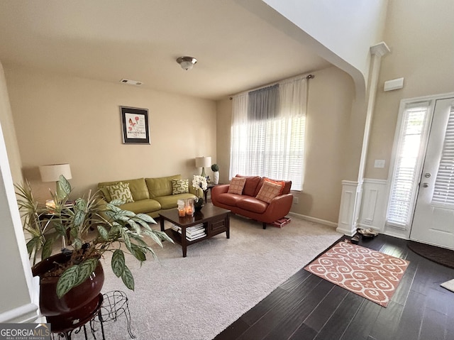 living room featuring decorative columns, wainscoting, visible vents, and wood finished floors