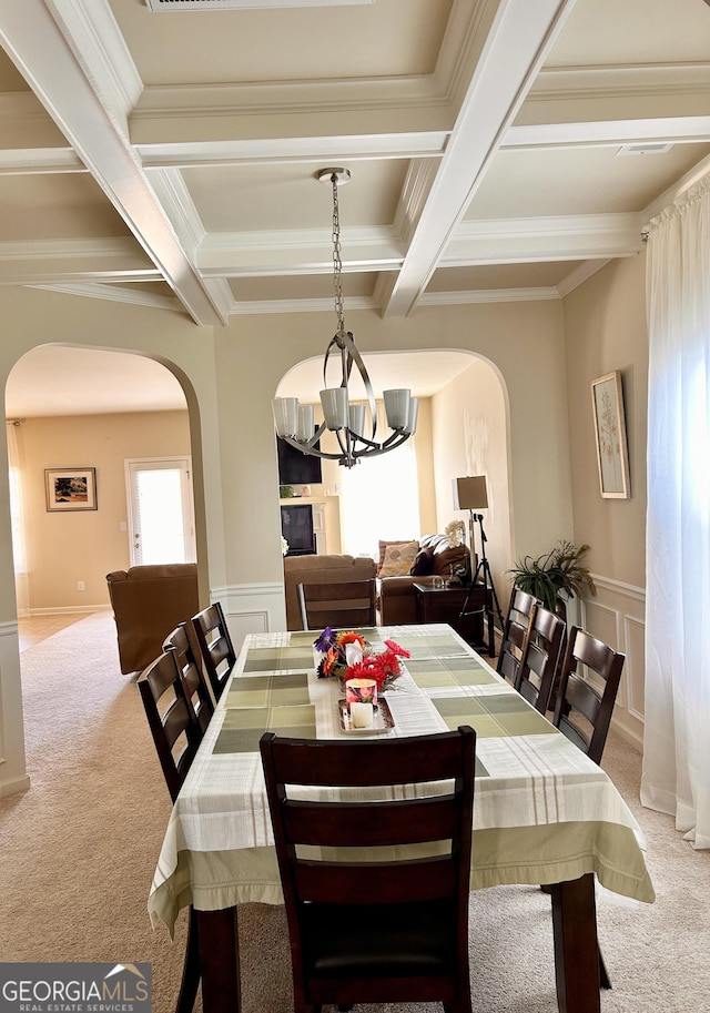 dining area with light carpet, arched walkways, and coffered ceiling