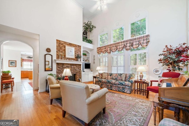 7420 Colony Ct, Cumming, GA 30041 - living room with a stone fireplace, a high ceiling, light wood-style floors, arched walkways, and built in shelves