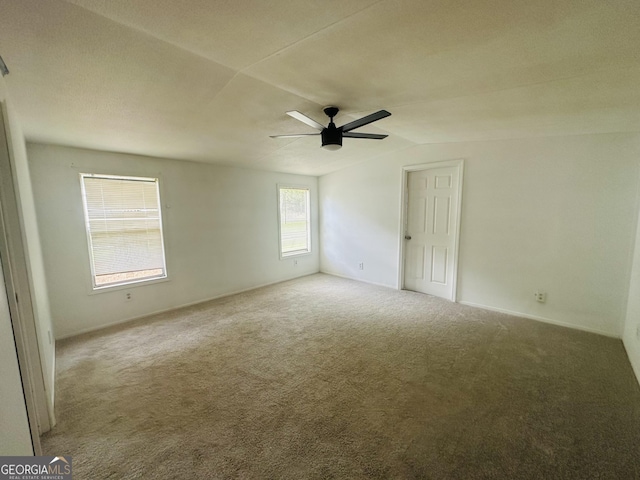 empty room with carpet floors, vaulted ceiling, a ceiling fan, and baseboards