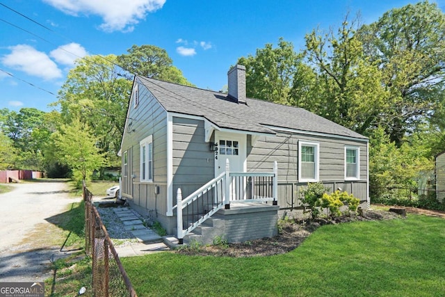 5024 Park Ave, Forest Park, GA 30297 - view of front of house with a front yard, a chimney, and a shingled roof