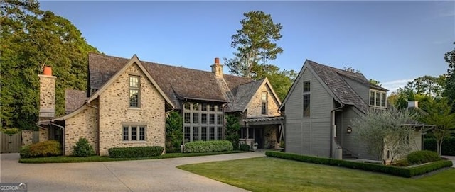 2979 Ridgewood Rd NW, Atlanta, GA 30327 - tudor-style house featuring a chimney, brick siding, concrete driveway, and a front yard