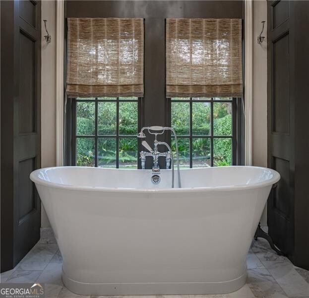 2979 Ridgewood Rd NW, Atlanta, GA 30327 - bathroom with marble look tile flooring, plenty of natural light, and a freestanding tub
