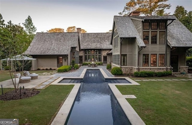 2979 Ridgewood Rd NW, Atlanta, GA 30327 - rear view of house featuring a chimney, a lawn, an outdoor pool, a patio, and stone siding