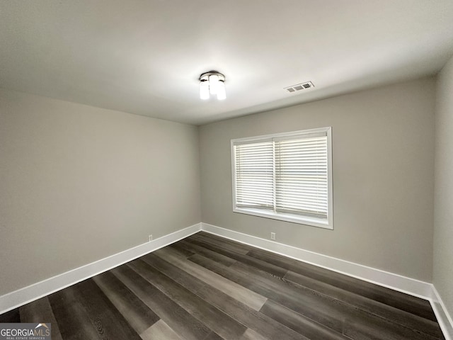 spare room with dark wood-style flooring, baseboards, and visible vents
