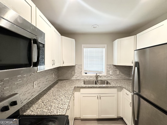 kitchen featuring tasteful backsplash, appliances with stainless steel finishes, a sink, and white cabinets