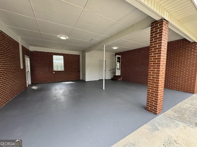 basement featuring brick wall and a paneled ceiling