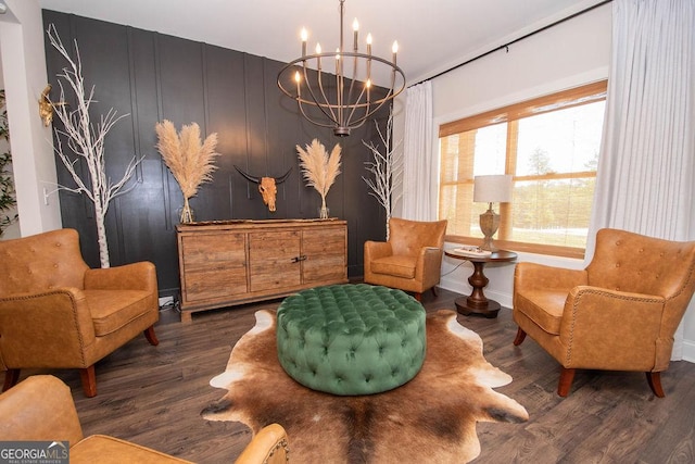 living area featuring wood finished floors, a notable chandelier, and baseboards