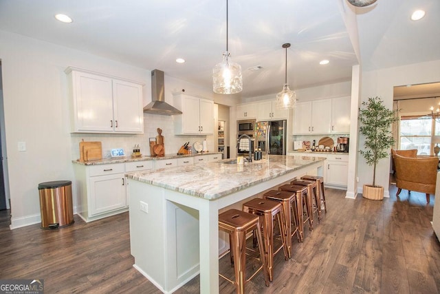 kitchen featuring fridge with ice dispenser, wall chimney exhaust hood, a sink, dark wood finished floors, and stainless steel microwave