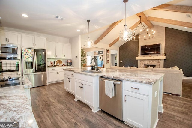 kitchen featuring visible vents, lofted ceiling with beams, a sink, open floor plan, and appliances with stainless steel finishes