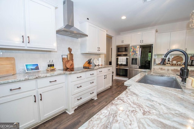 kitchen with exhaust hood, white cabinetry, appliances with stainless steel finishes, dark wood-style flooring, and a sink