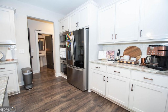 kitchen with tasteful backsplash, white cabinets, appliances with stainless steel finishes, and dark wood-style flooring