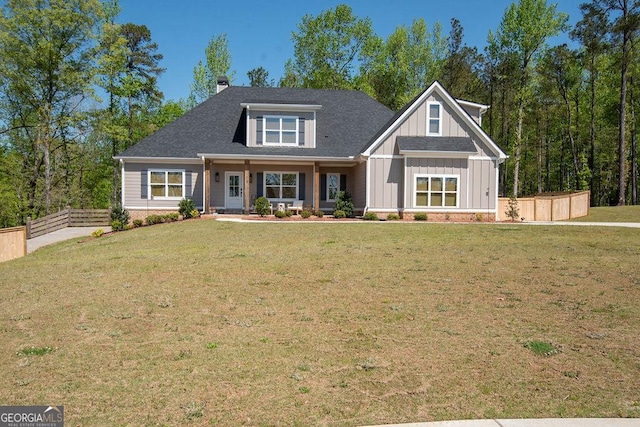 craftsman inspired home with roof with shingles, a chimney, board and batten siding, a front yard, and fence