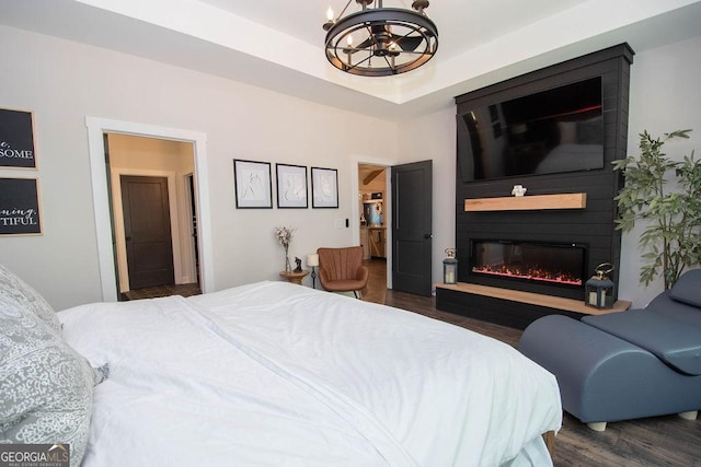 bedroom featuring a notable chandelier, a large fireplace, and dark wood-style floors