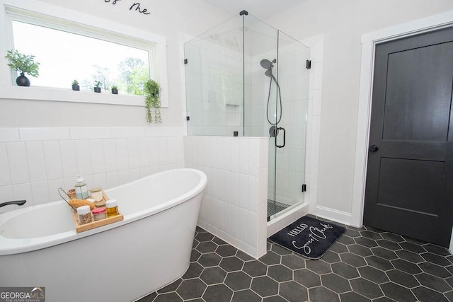 bathroom with a shower stall, a freestanding tub, and tile patterned flooring