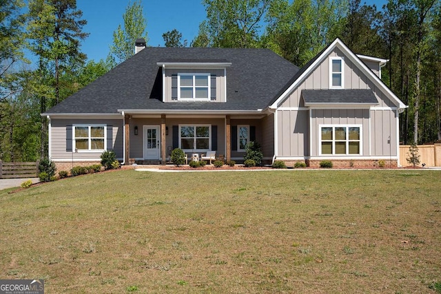 view of front facade featuring a front yard, fence, board and batten siding, and a chimney