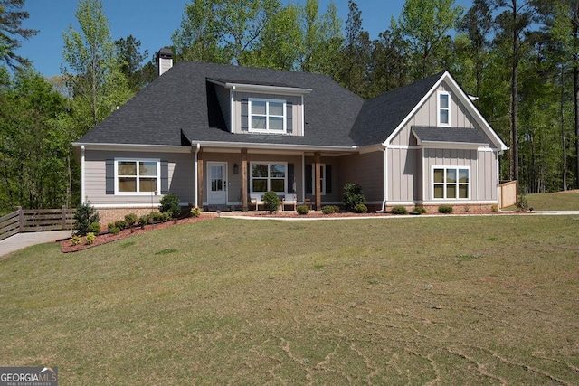 craftsman-style house featuring a chimney, board and batten siding, a front lawn, fence, and covered porch