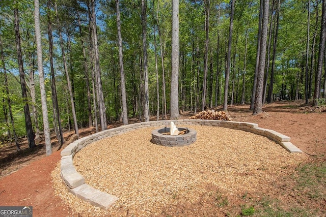 view of yard with a wooded view and an outdoor fire pit