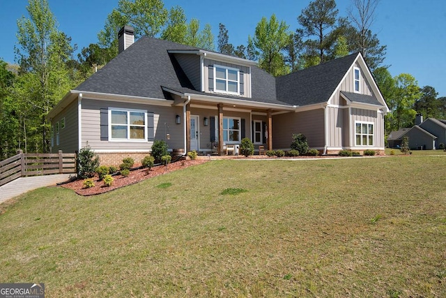 craftsman house with a chimney, fence, brick siding, a front lawn, and roof with shingles