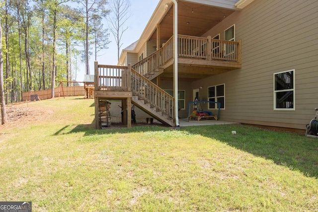 rear view of house with stairway, a patio area, a wooden deck, a yard, and fence