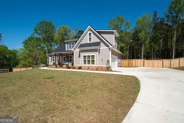 view of front of house with an attached garage, concrete driveway, fence, and a front lawn